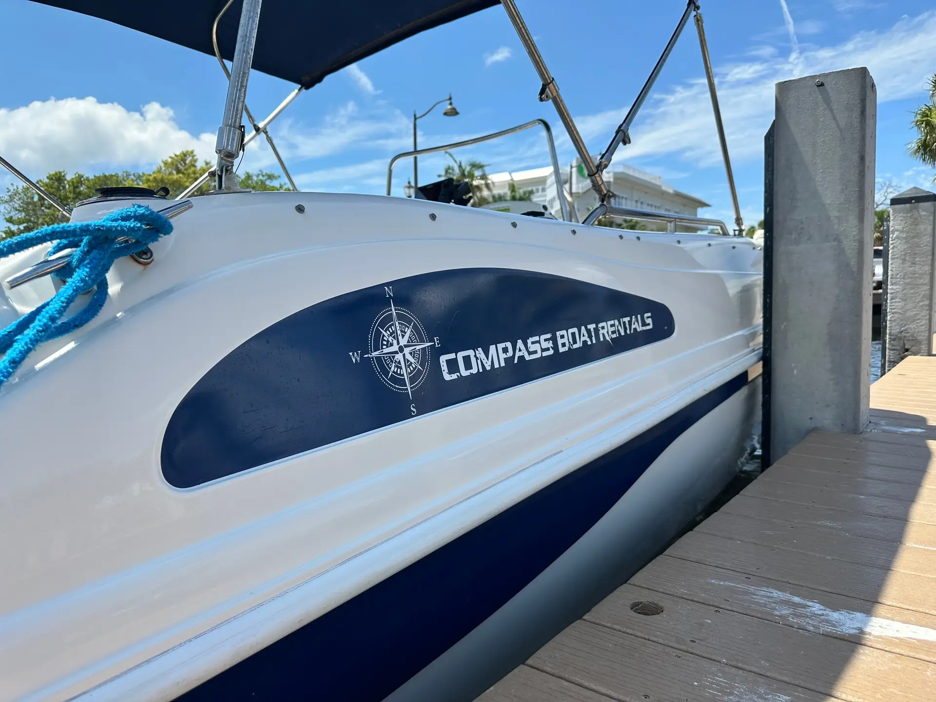 Compass Boat Rentals branding on the hull of the deck boat at the dock