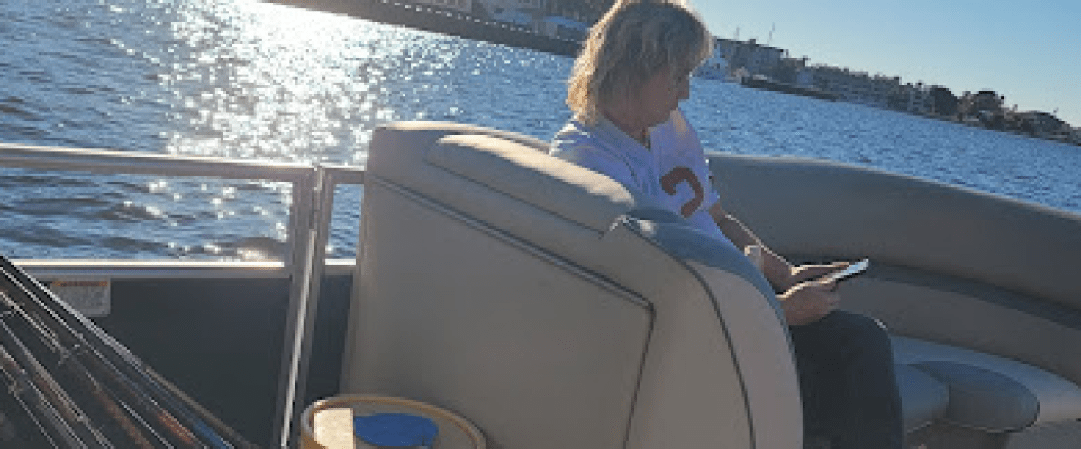 a woman sitting in a deck boat on a body of water